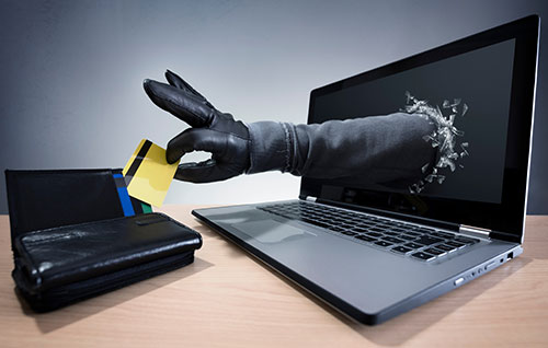 laptop with a gloved hand coming out of the screen and stealing a credit card from a wallet