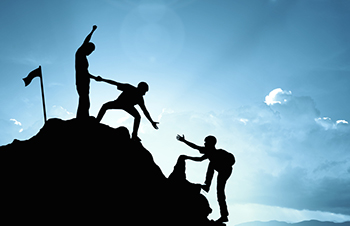 people helping each other climb a hill