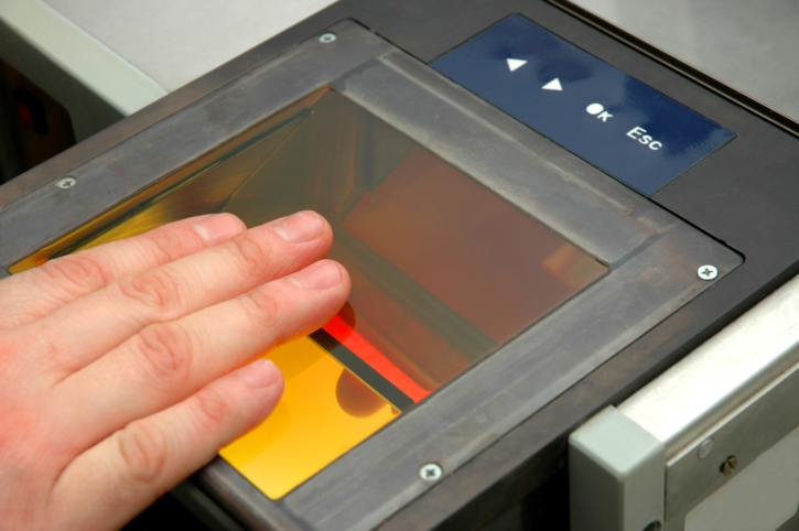 fingers placed on glass plate as light scans for fingerprints