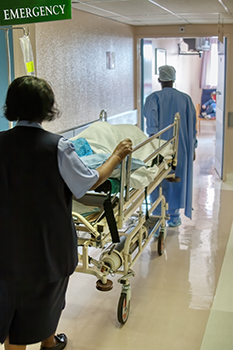 Hospital workers wheeling a person on a stretcher through a hospital