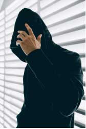 male in black hoodie with his hands covering his face
