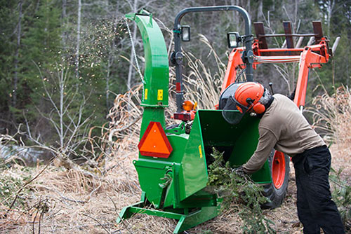 a person putting tree tops into a chipper