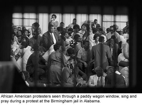 African American protesters seen through a paddy wagon window, sing and pray during a protest at the Birmingham Jail in Alabama.