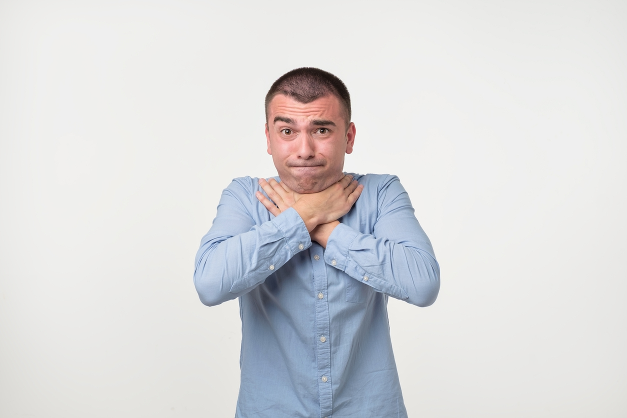 a man demonstrates the universal sign for choking