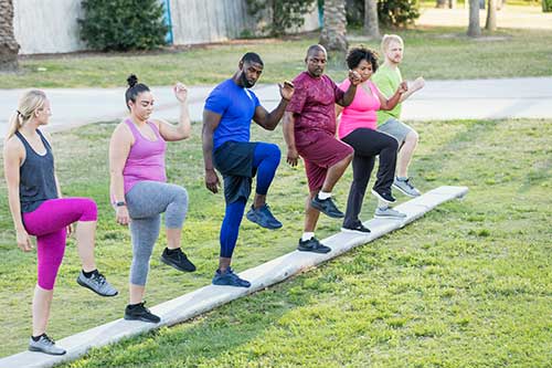 Group of people doing warm up exercises outside. 