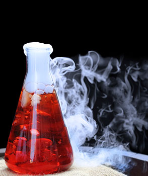 beaker with red liquid and white smoke