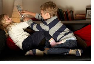 "Image of a boy and girl fighting over the TV remote"